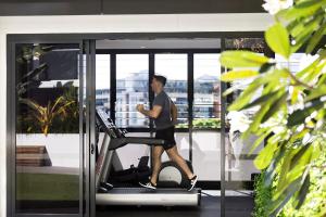 un homme qui marche sur un tapis de course dans une salle de sport dans l'établissement Alcyone Hotel Residences, à Brisbane