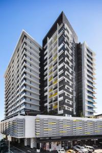 Un grand bâtiment noir et blanc avec des voitures devant lui dans l'établissement Alcyone Hotel Residences, à Brisbane