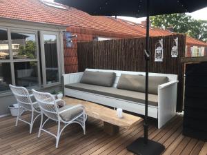 - un canapé sur une terrasse avec des chaises et un parasol dans l'établissement Bergenshofje, à Bergen