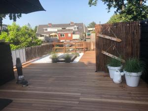 une terrasse en bois avec des plantes en pot et une clôture dans l'établissement Bergenshofje, à Bergen