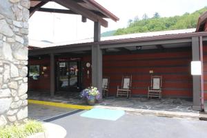 - un bâtiment rouge avec deux chaises et une porte fleurie dans l'établissement Great Smokies Inn - Cherokee, à Cherokee