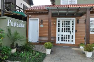 a wooden cabin with a white door and a gate at Pousada Villa Vecchia in Canela