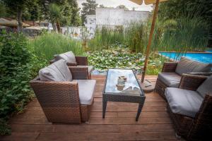 eine Terrasse mit Korbstühlen, einem Tisch und einem Sonnenschirm in der Unterkunft Renegade Hotel in Siófok