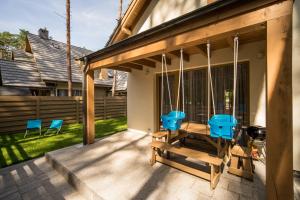 a porch with blue chairs and a swing at Villa Arkadia in Łukęcin