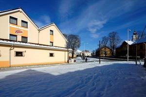 een met sneeuw bedekte straat voor een gebouw bij Penzión Valentína in Poprad