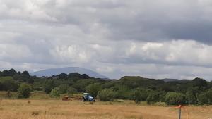 einem Traktor auf einem Feld mit einem Berg im Hintergrund in der Unterkunft Swallows Cottage in Swinford