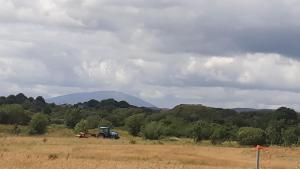 einem Traktor auf einem Feld mit einem Berg im Hintergrund in der Unterkunft Swallows Cottage in Swinford