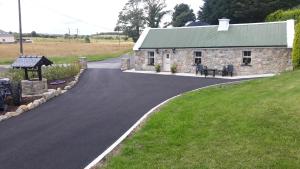 eine Straße, die zu einem Steingebäude mit einem Tisch führt in der Unterkunft Swallows Cottage in Swinford