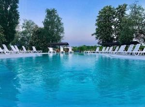 a large swimming pool with chairs and blue water at База відпочинку "РіверСайд" СВІТЛО Є ЗАВЖДИ in Novomoskovsʼk