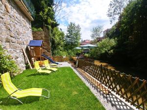 un patio con sillas de césped amarillas y un parque infantil en Hotel garni Paleta, en Škofja Loka