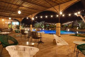 - une terrasse avec des tables et des chaises ainsi qu'une piscine la nuit dans l'établissement Agriturismo Li Calizzi Arte e Natura, à Novoli