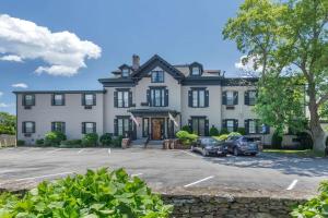 una grande casa con auto parcheggiate in un parcheggio di The Carriage House Inn Newport a Middletown