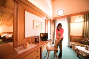 a woman standing in a hotel room with a desk at Villa Rier in Siusi