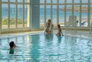 une femme et deux enfants assis dans une piscine dans l'établissement Residence Reine Marine, à Saint-Malo