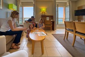 une femme et trois enfants assis autour d'une table dans un salon dans l'établissement Residence Reine Marine, à Saint-Malo