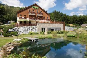 une maison avec un étang en face de celle-ci dans l'établissement Peras Wellness Hotel, à Ludvíkov