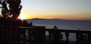 una puesta de sol sobre el océano con montañas en la distancia en Titicaca Chaska Wasi Amantani, en Ocosuyo