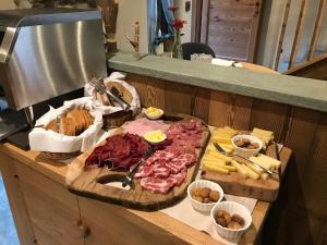 ArnadにあるAu coeur du village Chambres d'hôtes & SPAのチーズや肉などの食べ物を盛り付けたテーブル