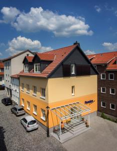 ein großes gelbes Gebäude mit schwarzem Dach in der Unterkunft Hotel Garni Am Kirchplatz in Ilmenau