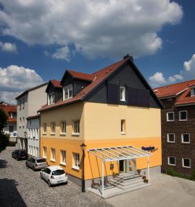 ein großes gelbes Gebäude mit schwarzem Dach in der Unterkunft Hotel Garni Am Kirchplatz in Ilmenau