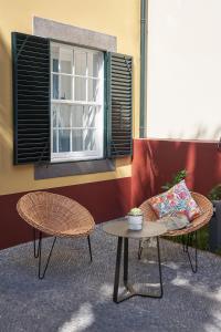 een patio met 2 stoelen, een tafel en een raam bij Good Memories Lodge in Funchal