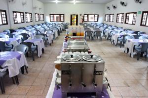 une salle remplie de tables et de chaises avec des nappes blanches dans l'établissement Hotel Águas Vivas, à Caraguatatuba