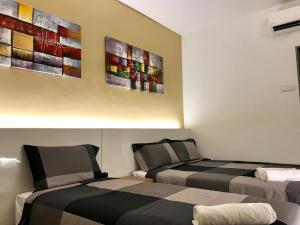 two beds in a room with paintings on the wall at RIVERO BOUTIQUE HOTEL Seremban 2 in Seremban