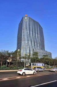 Un grand bâtiment avec des voitures garées devant lui dans l'établissement Estandon Hotel Guangzhou, à Canton