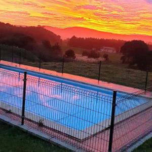 une grande piscine avec un coucher de soleil en arrière-plan dans l'établissement Apartamentos La Pradera de Isla, à Isla