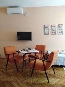 uma sala de estar com uma mesa e cadeiras e uma televisão em Sobe Gajić Sremski Karlovci em Sremski Karlovci