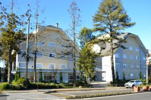 un gran edificio blanco con árboles delante de él en Sky Premium Hotel Gramado - Ótima Localização, en Gramado