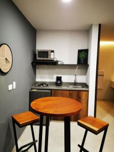 a small kitchen with a wooden table and two stools at Kapital Suites in Pereira