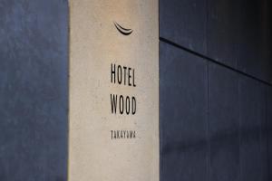 高山HOTEL WOOD TAKAYAMA的建筑一侧的一个标牌,上面写着酒店木材