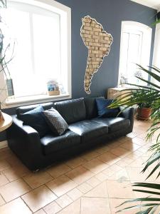 a black leather couch in a living room with a brick wall at Blue Doors Hostel KTV in Rostock