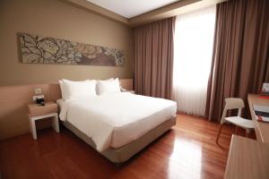 Un dormitorio con una gran cama blanca y una ventana en Swiss-Belinn Airport Jakarta, en Tangerang