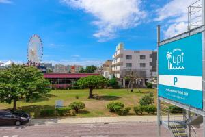 a sign in a park with a ferris wheel in the background at Condominium Hotel Mihama Upi in Chatan