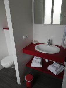 a bathroom with a sink and a toilet and a mirror at Hôtel-restaurant Les Colonnades in Saint-Fulgent