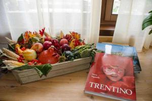 een boek en een mand met groenten en fruit op een tafel bij Garnì San Giorgio Della Scala Rooms and Breakfast in Trento