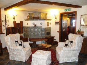 a living room with two chairs and a fireplace at Hotel Bellevue in Champoluc