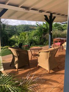 una terraza de madera con sillas de mimbre y una mesa en Agréable appartement à 2 pas des plages, en Le Gosier