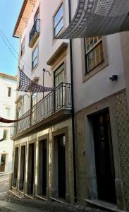 Change The World Hostels - Coimbra - Almedina في كويمبرا: مبنى بشرفة ومظلة على شارع