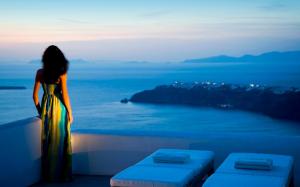 a woman standing on a ledge looking at the ocean at White Santorini in Imerovigli