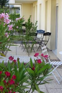 een patio met tafels, stoelen en bloemen bij Résidence Carouge Appart Hôtel in Brétigny-sur-Orge