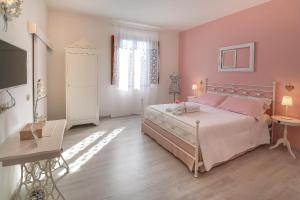 - une chambre avec un grand lit, des murs roses et du parquet dans l'établissement B&B Ulivo Gaio, à San Miniato