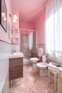 une salle de bains rose avec toilettes et lavabo. dans l'établissement B&B Ulivo Gaio, à San Miniato