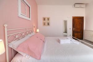 - une chambre avec un lit blanc aux murs roses dans l'établissement B&B Ulivo Gaio, à San Miniato