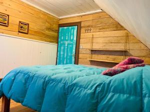 Una cama azul en una habitación con paredes de madera. en Casa Apel Hostel, en Puerto Varas