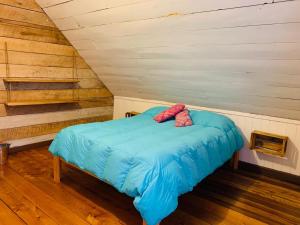 1 cama con 2 almohadas rosas en una habitación en Casa Apel Hostel, en Puerto Varas