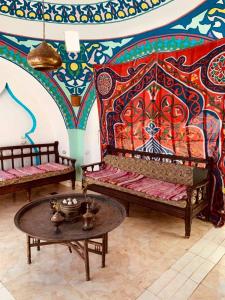 Cette chambre comprend deux bancs et une table avec un mur coloré. dans l'établissement Cleopatra Hotel Luxor, à Louxor