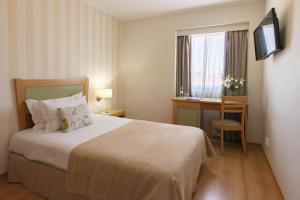 a hotel room with a bed and a desk and a television at Luna Esperanca Centro Hotel in Setúbal